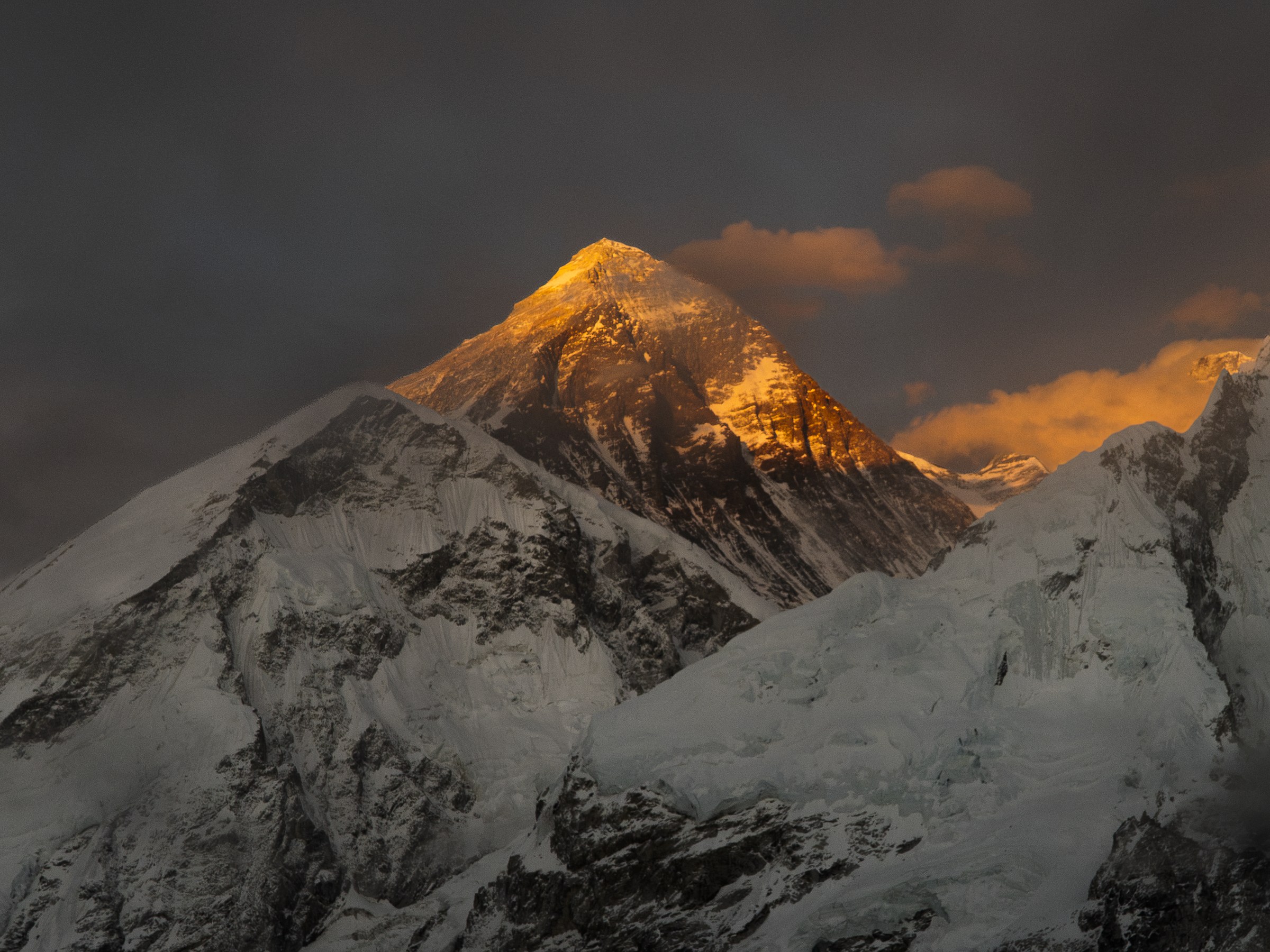 Mount Everest at sunrise, golden light on the summit above snow-covered Himalayan ridges